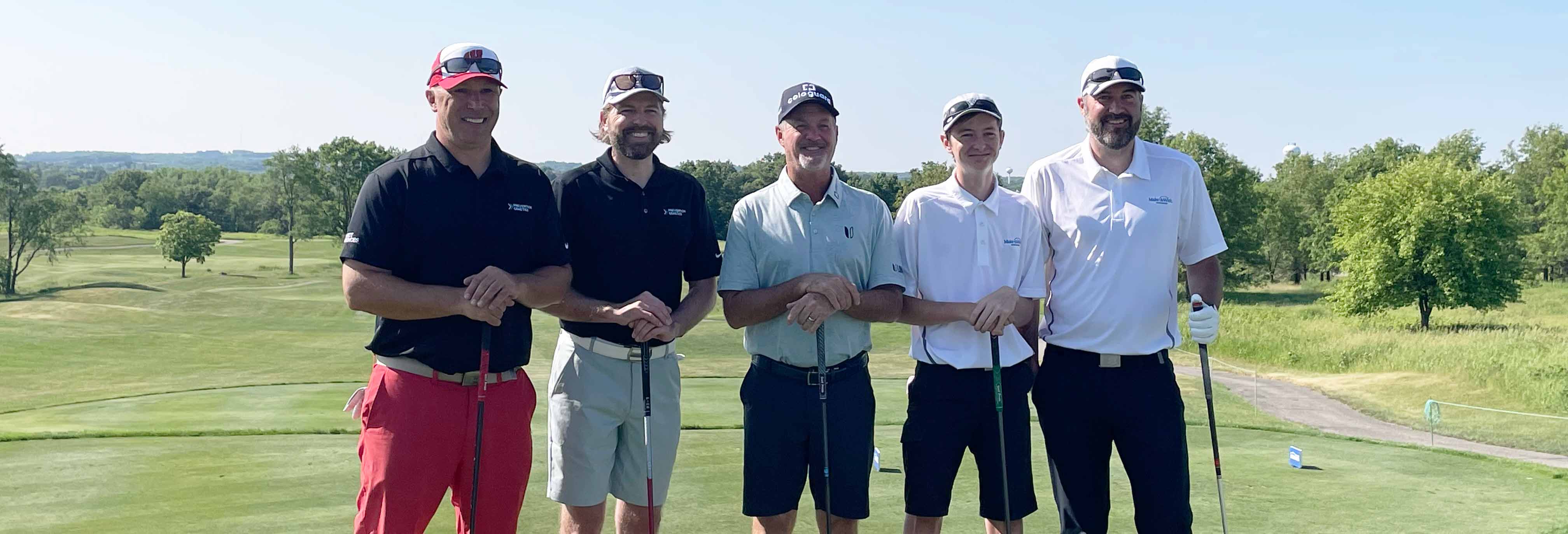 Group of five golfers standing at golf course