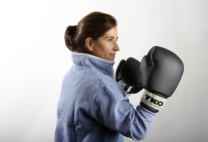 Elizabeth S. wearing black TKO boxing gloves in front of white background