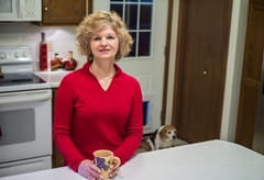 Nancy S. Standing in her kitchen holding a pink mug