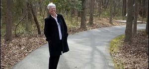 Suzie W standing on forest road with the words Suzie researched the test online and was determined to ask her oncologist about it.